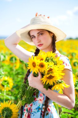 Ayçiçeği tarlasında hasır şapkalı güzel bir kadın.