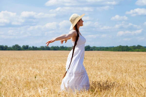 Jovem morena de vestido branco andando em um campo de trigo — Fotografia de Stock