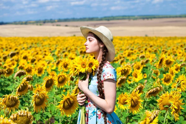 Joven hermosa mujer en un sombrero de paja en un campo de girasoles — Foto de Stock