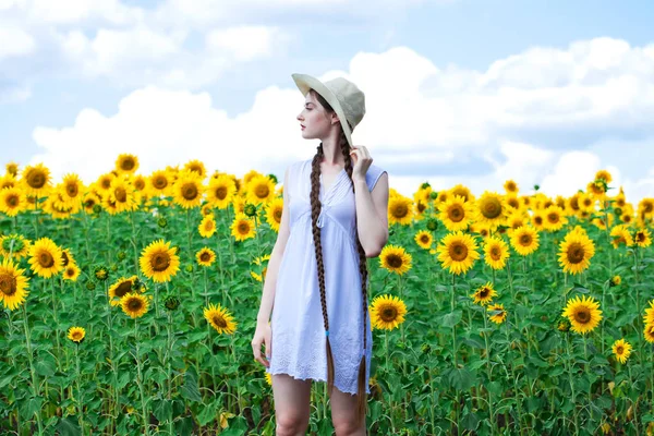 Young beautiful woman in a straw hat in a field of sunflowers — Stock Photo, Image