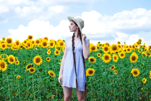 해바라기 밭의 밀짚모자를 쓰고 있는 아름다운 소녀 — 스톡 사진