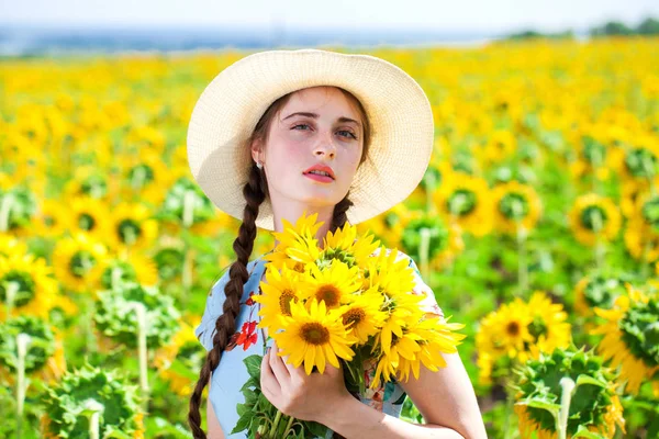 年轻美丽的女人戴着草帽在葵花园子里 — 图库照片