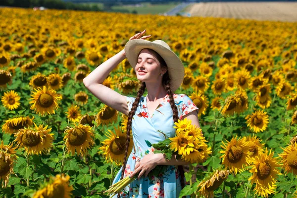 Młoda piękna kobieta w słomkowym kapeluszu na polu słoneczników — Zdjęcie stockowe