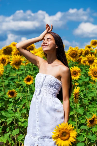 Ung vacker flicka i ett fält av solrosor fält — Stockfoto