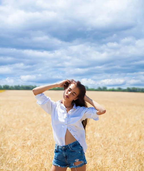Young brunette woman in a white shirt and jeans shorts — Stock Photo, Image