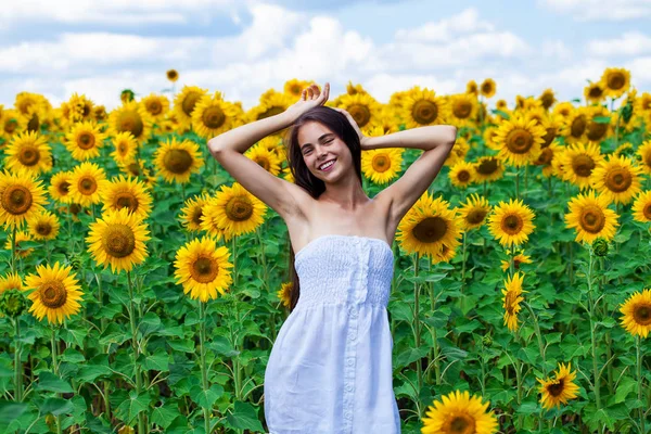 Ung vacker flicka i ett fält av solrosor fält — Stockfoto