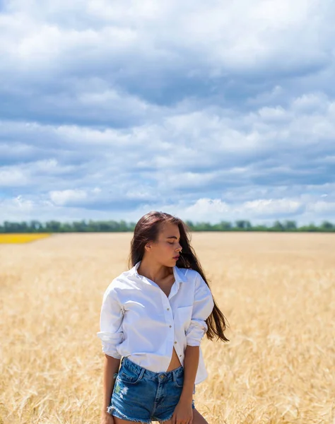 Mulher morena jovem em uma camisa branca e calções de ganga — Fotografia de Stock