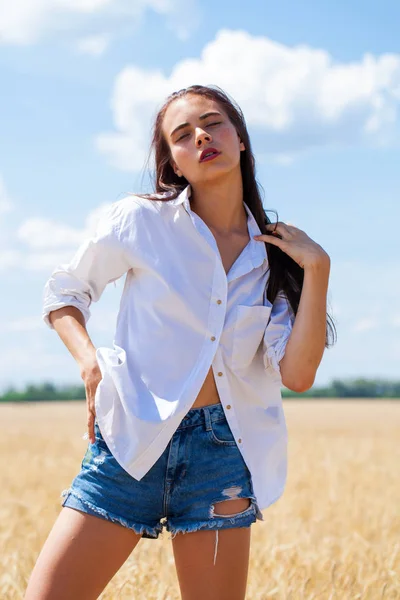 Mulher morena jovem em uma camisa branca e calções de ganga — Fotografia de Stock