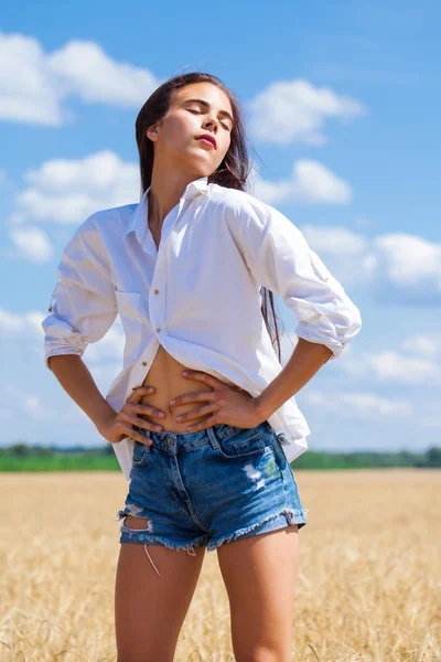 Giovane donna bruna in camicia bianca e pantaloncini jeans — Foto Stock