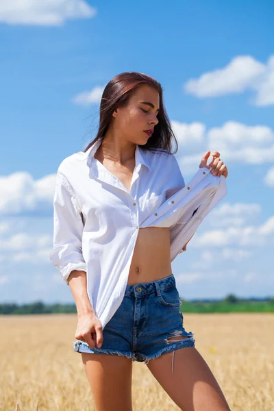 Młoda brunetka kobieta w białej koszuli i dżinsy spodenki — Zdjęcie stockowe