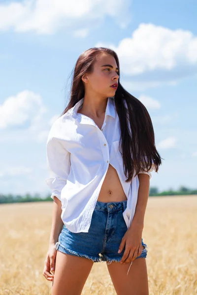 Mujer morena joven en una camisa blanca y pantalones cortos vaqueros —  Fotos de Stock