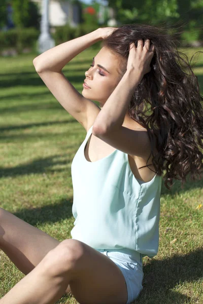 Mladá brunetka v tyrkysové blůze, která sedí na g — Stock fotografie