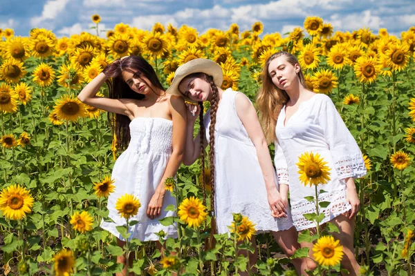 Tre unga kvinnor i vit klänning poserar mot den blå himlen i — Stockfoto