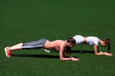 Parktaki yeşil çimlerin üzerinde egzersiz yapan, tahta kayış pozunda duran güzel, sağlıklı genç bayanları tatmin ederdi. Açık hava, spor yaşam tarzı, yoga zamanı, sağlık kilo kaybı