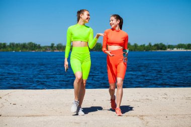 Mavi gökyüzüne karşı spor giyim trenlerinde genç ve güzel bir fitness modelinin vücut portresi.