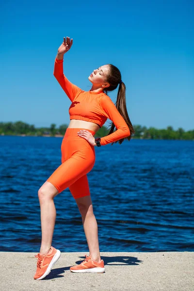 若いアスレチック女性の完全な体の肖像画はヴォルガ川のほとりで物理的な演習を行います — ストック写真