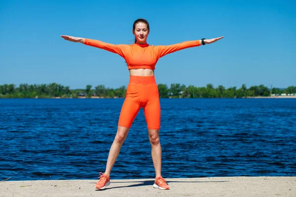 若い運動選手の女の子はヴォルガ川のほとりで物理的な演習を行います — ストック写真