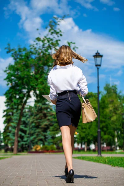 一个身穿白衬衫和黑色裙子的年轻女商人的画像在一个夏季公园里散步 — 图库照片