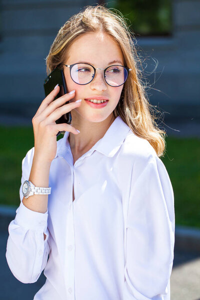 Портрет молодого ассистента в белой блузке, звонящего по улице