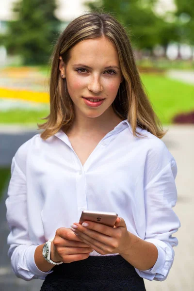 Portrét Mladé Asistentky Bílé Blůze Telefonem Ruce Pózující Venku — Stock fotografie