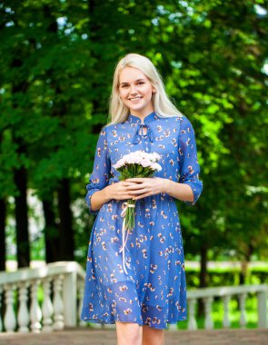 Mavi çiçekli güzel bir kızın portresi. Yaz parkında yürüyen bir elbise.