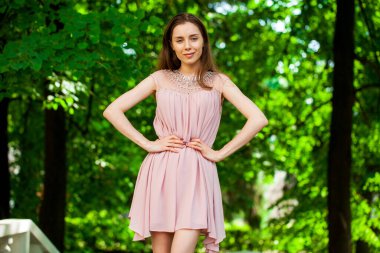 Bej elbiseli, yaz caddesinde poz veren güzel bir esmer kadının vücut portresi.