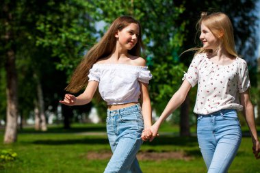 İki komik kız arkadaş yaz parkında yürüyor..
