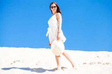Beyaz elbiseli güzel esmer bir kadının vücut portresi.