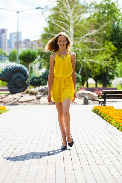 フルボディポートレートの若いですブロンド女性で黄色ドレス歩行で夏公園 — ストック写真