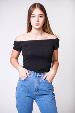Gri arka planda izole edilmiş mavi kotlu güzel bir kızın yakın plan portresi.