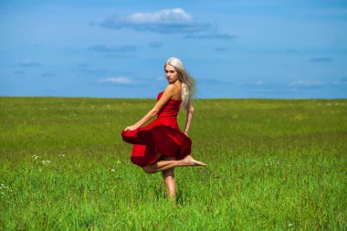 Kırmızı elbiseli güzel sarışın bir kadının vücut portresi.