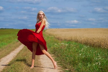 Kırmızı elbiseli güzel sarışın bir kadının vücut portresi.