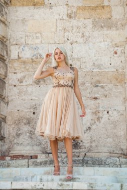 Bej elbiseli güzel sarışın bir kadının vücut portresi.