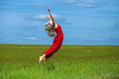 Kırmızı elbiseli güzel sarışın bir kadının vücut portresi.