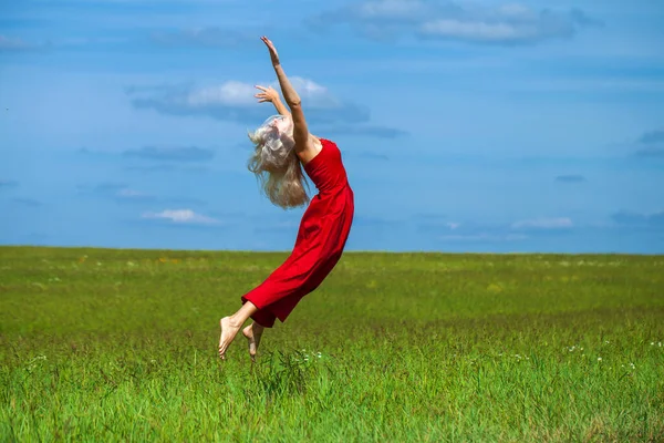 Kırmızı elbiseli güzel sarışın bir kadının vücut portresi.