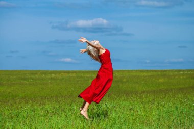Kırmızı elbiseli güzel sarışın bir kadının vücut portresi.