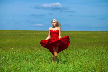 Kırmızı elbiseli güzel sarışın bir kadının vücut portresi.