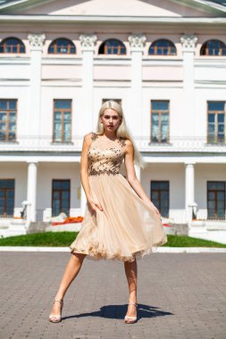 Tam vücut portresi. Yazlık elbise giymiş güzel bir sarışın kadın. Açık hava.