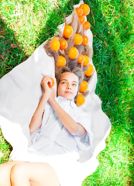 Genç Kız Çimenlikte Bir Battaniyeye Uzanmış Saçında Portakallarla — Stok fotoğraf