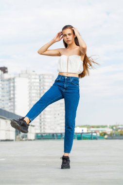 Kot pantolonlu güzel, esmer bir kadının vücut portresi.