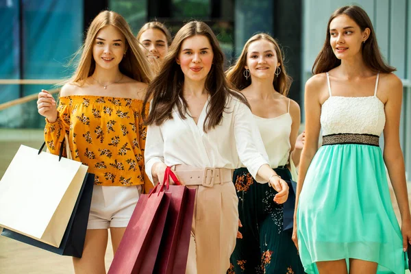 Mutlu genç kız arkadaşlar alışveriş merkezinde yürüyor.