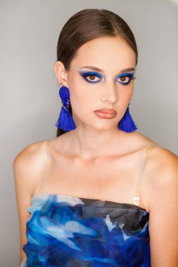 Gri arka planda izole edilmiş güzel esmer bir modelin yakın portresi.
