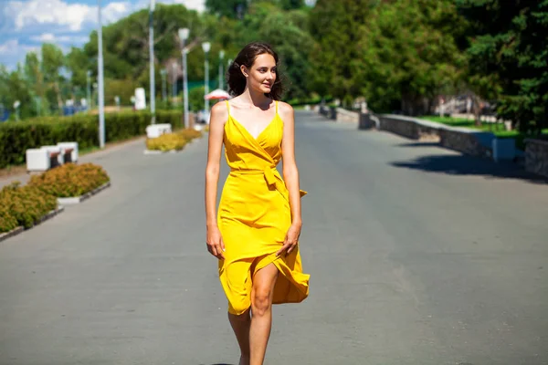 夏の公園を歩く黄色のドレスの若いブロンドの女性の肖像画を閉じます — ストック写真