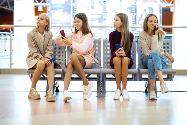 Vier Junge Mädchen Sitzen Auf Der Bank Vergraben Ihren Smartphones — Stockfoto