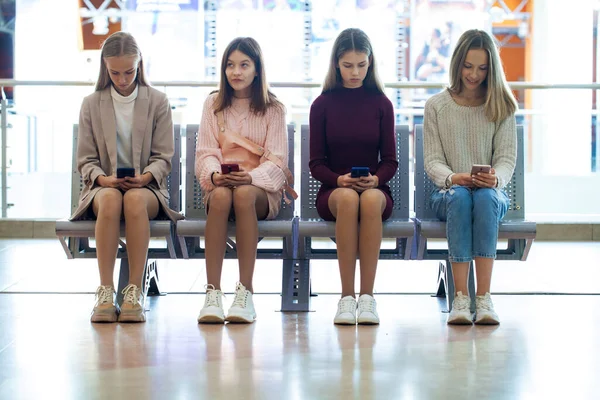Tam Boy Portre Dört Genç Kız Bankta Oturuyorlar Akıllı Telefonlarıyla — Stok fotoğraf