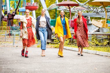 Sonbahar parkında yürüyen dört manken. 