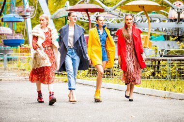 Sonbahar parkında yürüyen dört manken. 