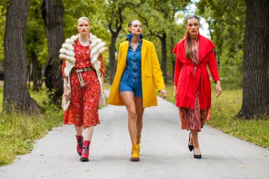 Sonbahar parkında yürüyen üç manken.