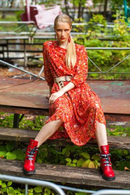 Moda modeli portresi. Parlak kırmızı elbiseli genç bir kız poz veriyor, sonbahar parkında.