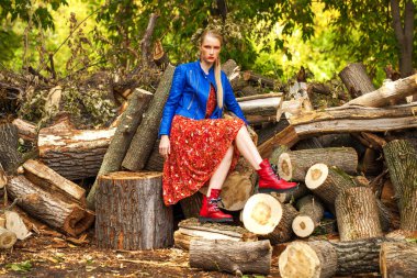 Rus güzellik kadını. Uzun kırmızı çiçekli, mavi ceketli şık bir mankenin vücut portresi.